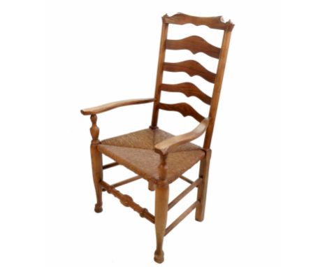 A 19th century ladder back armchair, with rush seat, raised on turned legs united by stretchers