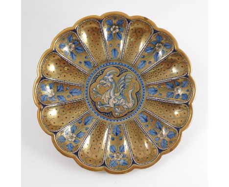 An Italian pottery shaped circular dish, the centre decorated with a mythical beast, the scalloped edge with alternate panels