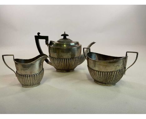 A George V hallmarked silver three piece tea set of oval part gadrooned form, Birmingham, 1910, length of teapot 22.5cm, comb