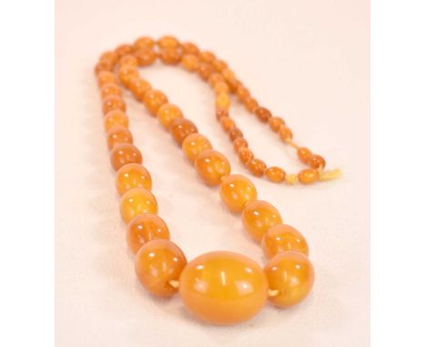 A vintage hand tied graduated egg yolk/butterscotch amber bead necklace formed of fifty-five beads, length approx 86cm, the l