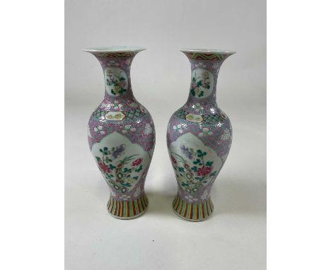 A pair of late 19th/early 20th century Chinese Famille Rose lilac ground baluster vases, each painted with opposing vignettes