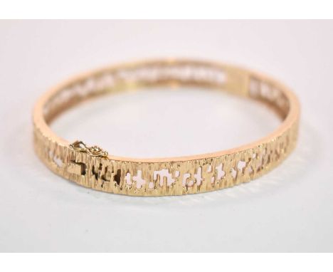A 9ct yellow gold textured and pierced oval hinged snap bangle, internal width 60mm, approx. 16.2g.