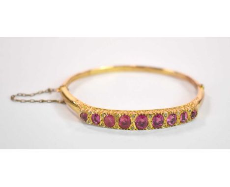 A late Edwardian 9ct yellow gold morganite and diamond chip hinged oval snap bangle with scroll setting, Chester, 1910, inter