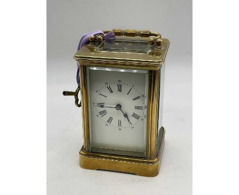 A circa 1900 French brass carriage clock with Roman numerals to the white enamel dial, case door numbered 79, height 12.5cm.