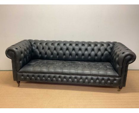 A late 20th century black leather Chesterfield sofa with button back detail and studded front raised on four turned supports 