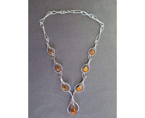 A very pretty amber and silver studio necklace, the amber polished to the form of raindrops with a silver shroud around them,