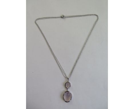 A rose quartz and diamond pendant, designed as two oval rose quartz faceted cabochons with single cut diamond detail suspende