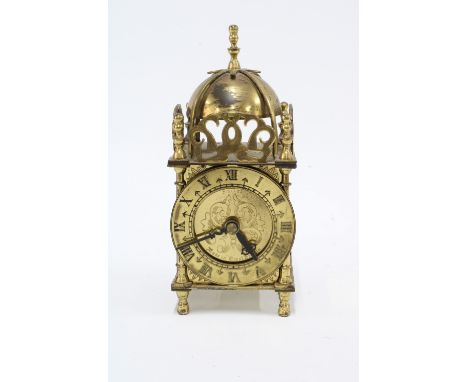 A small Smiths brass mantle clock, lantern style with domed to and chapter ring with roman numerals, standing on bun feet, 18