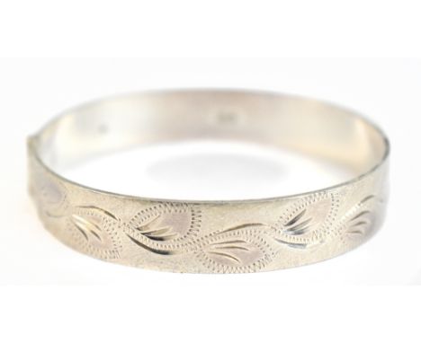 An Elizabeth II hallmarked silver hinged bangle with leaf decoration to the textured upper band, Birmingham 1972, internal wi