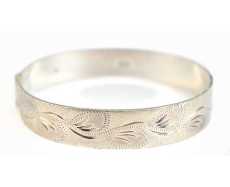 An Elizabeth II hallmarked silver hinged bangle with leaf decoration to the textured upper band, Birmingham 1972, internal wi