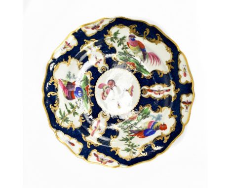 WORCESTER; an 18th century shallow shaped bowl with blue scale ground and vignettes decorated with large birds, butterflies a