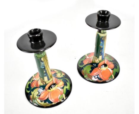 MOORCROFT; a pair of floral tube line decorated candlesticks on spreading circular feet, impressed marks and year for 2007 to