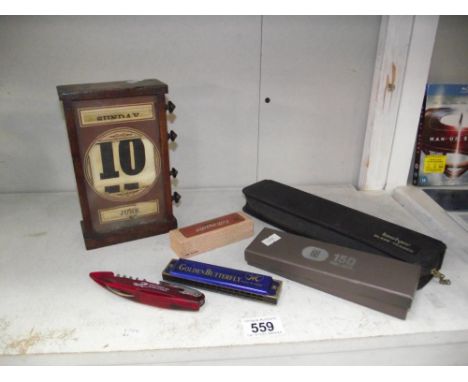 A wooden turning perpetual calendar, a harmonica, Kershaw blade trader etc.,