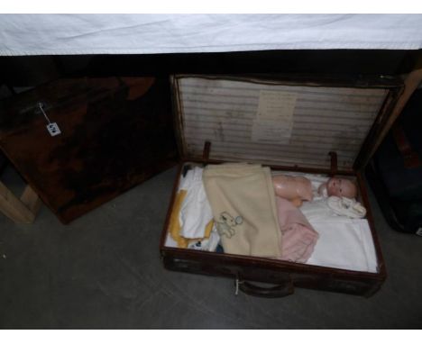 A vintage case containing various household textiles and linens including napkins, children's vintage clothing, doll (a/f) an