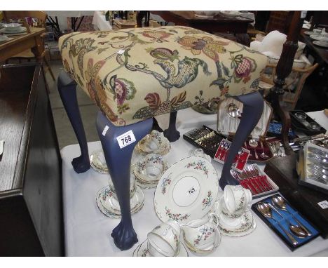 A tapestry covered stool with painted legs on ball and claw feet.