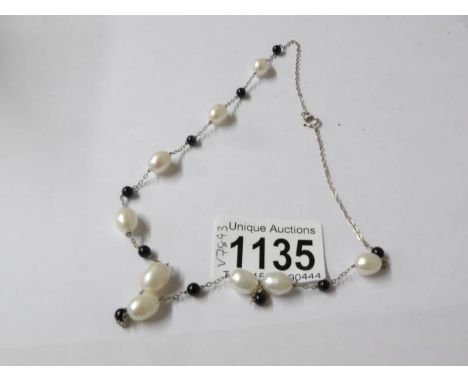 A freshwater pearl necklace with onyx spacers set in silver.