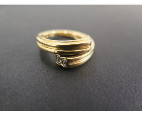 An 18ct gold diamond crossover ring - The grooved band with brilliant-cut diamond cluster terminations - Hallmarked London - 