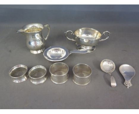 A silver jug, a silver bowl, two pairs of silver serviette rings, two silver caddy spoons and a continental silver strainer a