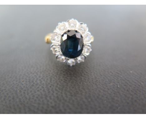 An 18 ct gold diamond and sapphire ring - the central oval sapphire measuring approx. 9.5 mm x 8 mm - surrounded by  ten roun