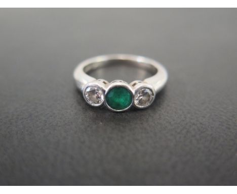 A platinum emerald and diamond three-stone ring - The circular emerald and brilliant-cut diamonds within a collet setting  - 