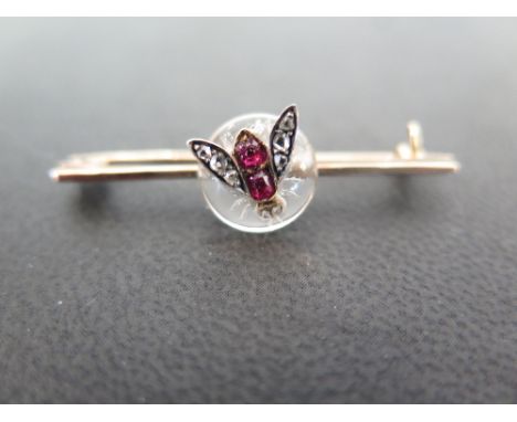 A ruby and diamond fly bar brooch - Mounted on a circular rock crystal panel - Tests as gold - Length 3.8cms - Weight approx 