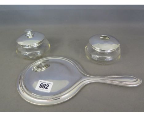 Three silver dressing table items comprising hand mirror and two trinket pots hallmarked Birmingham 1920 and 1923 - weighable