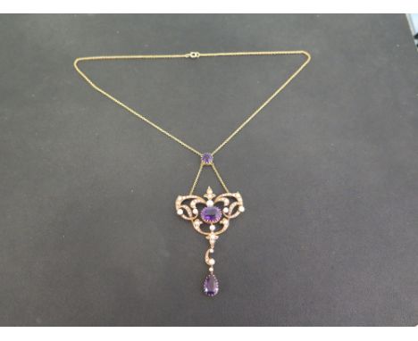 An early 20th century 15ct gold amethyst and seed pearl pendant - The oval amethyst within a seed pearl openwork scroll surro