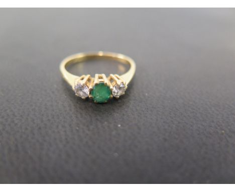 An 18ct gold emerald and diamond three-stone ring - The circular emerald and brilliant-cut diamonds to the plain band - Parti