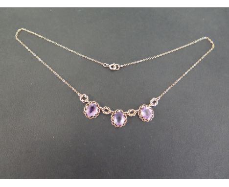 A 9ct gold amethyst necklace - The three oval amethysts to the floral spacers and belcher-link chain - Partial hallmark - Len
