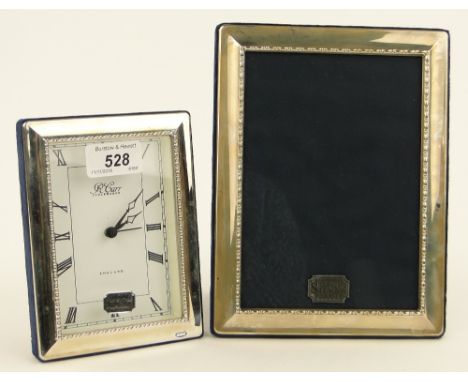 A modern silver framed clock and similar photo frame.