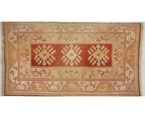 Turkish Milas Karyola wool rug, the brick-red field with three flower-bordered lozenges, within sand-coloured meander borders