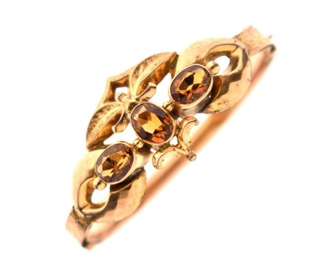 Victorian citrine hinged bangle, the three faceted oval cuts within a foliate engraved band, the lower section hallmarked 9ct