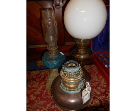 A Victorian oil lamp with blue glass reservoir and ornate pyramid cast iron bass together with two copper and brass oil lamps