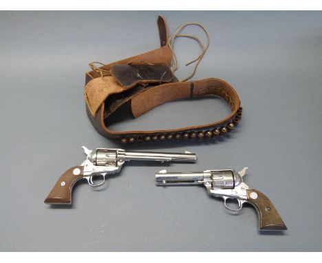A pair of Colt replica .45 six shot revolvers, one in a leather holster with ammunition belt and replica bullets