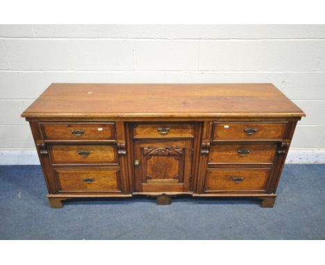 AN EARLY 20TH CENTURY OAK SIDEBOARD, with seven drawers, and central cupboard door, width 163cm x depth 50cm x height 78cm (c