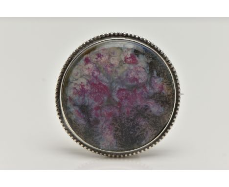 A WHITE METAL ‘RUSKIN’ BROOCH, of a circular form, painted ceramic insert, signed to the reverse ‘Ruskin England’, collet set