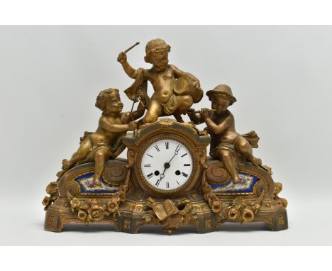 A SECOND HALF 19TH CENTURY GILT METAL FIGURAL MANTEL CLOCK INSET WITH PAINTED PORCELAIN PANELS, cast with three putti musicia