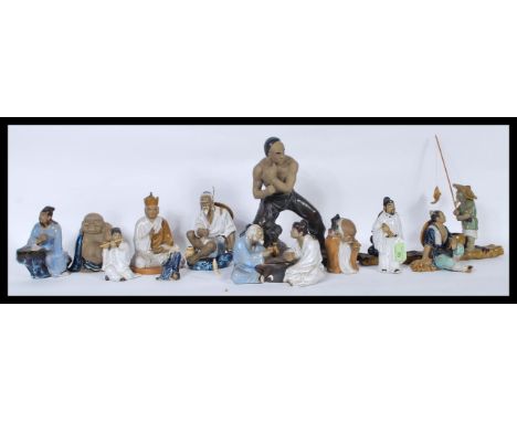 A group of Chinese figures made of light brown clay with some areas left natural and others glazed. The figures depicting var