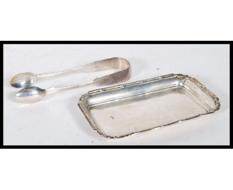 A silver hallmarked card tray and silver pair of tongues. The card/ pin tray having scroll and leaf decoration, hallmarked fo