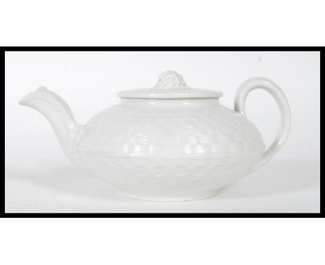 An 19th century Wedgwood caneware teapot having basket weave moulding, the flat lid with wheatsheaf finial. Impressed marks t