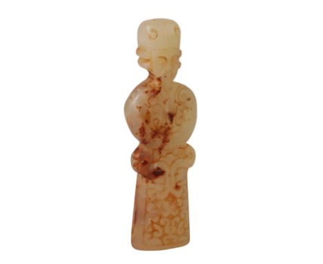 A CHINESE PALE CELADON JADE FIGURE OF AN OFFICIAL standing with arms folded wearing a tall headdress and robes decorated with