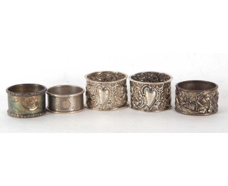 A pair of late Victorian silver serviette rings elaborately embossed with cherubs, scrolls etc, around an initialled cartouch