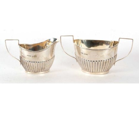 An Edwardian silver cream jug and twin handled sugar bowl oval shaped with part fluted design, Sheffield 1909, makers mark fo