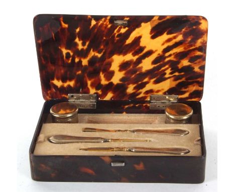 A George V silver manicure set in a tortoiseshell fitted box with silver hallmark hinges to the lid, contents to include two 