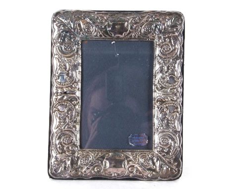 An Elizabeth II silver mounted photograph frame of rectangular form embossed with leaves and scrolls around two vacant cartou
