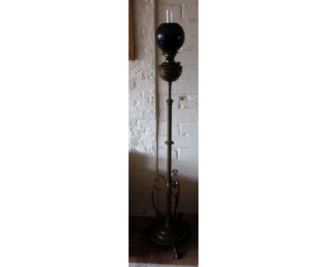 A Victorian brass floor standing oil lamp with dark red shade