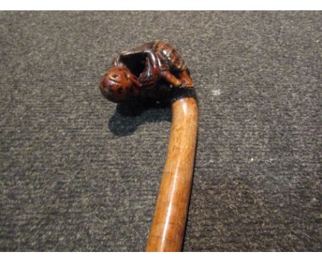 A walking stick with figural handle depicting man dressed as leopard eating another man. Thought to be a reference to the Leo