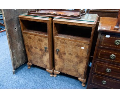 PAIR OF BURR WALNUT BEDSIDE CABINETS each with rounded oblong top above an open shelf and cupboard door, raised on short cabr