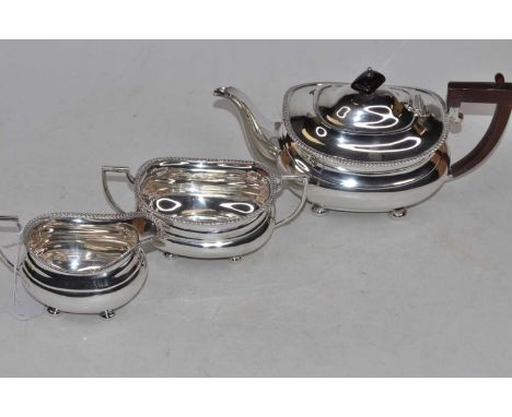 A George V silver three-piece tea service, the teapot of squat oval form, with gadrooned edge, bakelite handle and presentati
