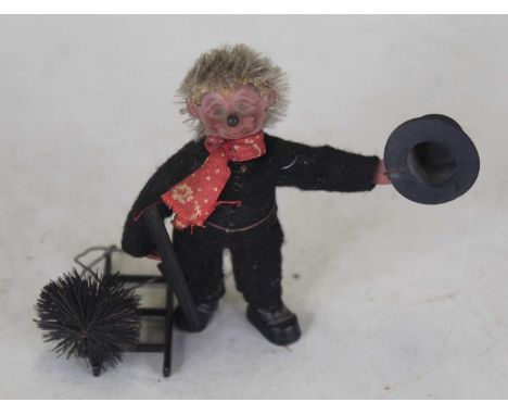 A miniature cloth covered figure modelled as a chimney sweep with hat in hand and various tools